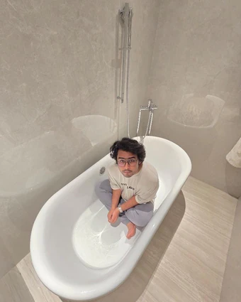 Sitting cross-legged in a white bathtub for a shoot
